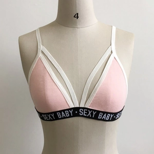 Détail de brassière rose avec bordure blanche et bande élastique noire avec texte SEXY BABY