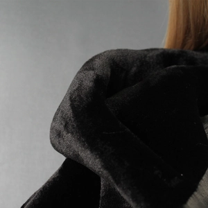 Close-up detail of smooth black faux fur texture on a hooded short jacket for women