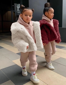 Outdoor street view of children's faux fur coats with hooded sweatshirts and sneakers