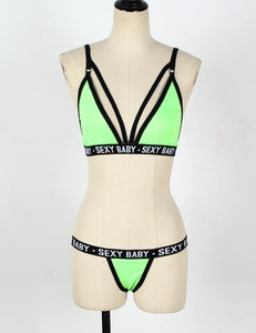 Detail of neon green bikini top with black straps and SEXY BABY text on the band