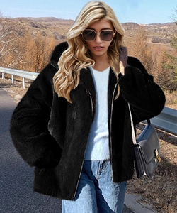 Detail of a black hooded faux fur jacket featuring a metal zipper and soft plush texture
