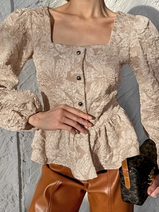 Detail shot of beige jacquard top with puff sleeves and embossed floral texture