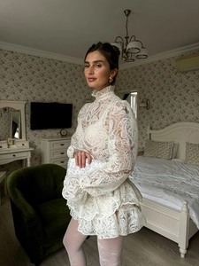 Dettaglio del top in pizzo bianco e gonna a balze con intricati motivi ricamati a traforo