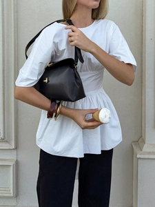 Détail du haut blanc à manches bouffantes avec taille plissée et ourlet à volants