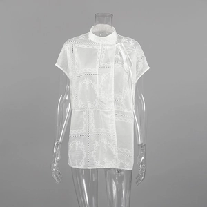 Detalle de blusa blanca de manga corta con bordado calado y cuello con lazo ajustable