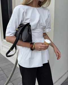 Détail du chemisier blanc à manches courtes avec plis à la taille et coupe moderne