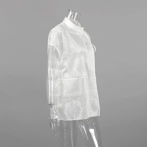 Primer plano detallado de bordado floral y patrones calados geométricos en camisa blanca de mujer