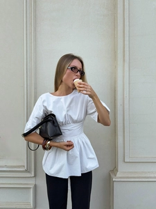 Détails d'un chemisier blanc à manches courtes avec taille plissée et ourlet évasé