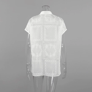 Detalle de camisa blanca bordada con motivos florales calados y diseño de encaje hueco