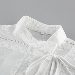 Detalle de cuello mao blanco bordado con calado de encaje y cordón de amarre