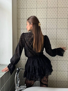 Dettaglio del top in pizzo nero e della gonna a balze con eleganti motivi floreali
