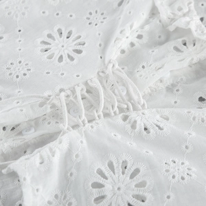 Dettaglio di camicia in cotone bianco con ricamo inglese, lacci e ricami floreali