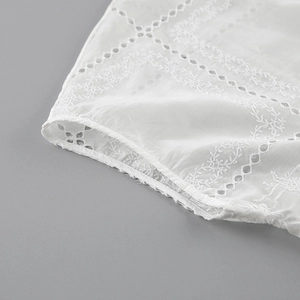 Primer plano de los bordados suizos y detalles calados en una camisa de algodón blanco fino