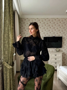 Dettaglio del set con top in pizzo nero trasparente e gonna corta a balze in pizzo coordinata