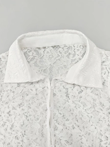 Close-up of white lace shirt collar with floral patterns and pearl-style buttons