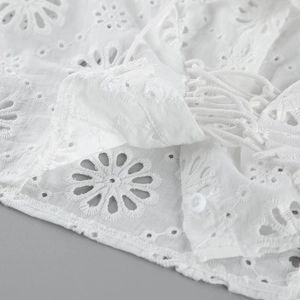 Dettaglio del ricamo inglese in cotone bianco con bottoni e design con coulisse
