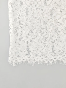 Detailed macro shot of white floral lace fabric with delicate eyelash trim finish