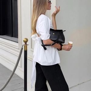 Elegante camicetta bianca con maniche a sbuffo, fiocco sul retro e borsa in pelle nera
