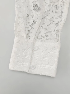 Close-up of white floral lace shirt cuffs with dual button closure and fringe detail