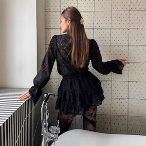 Elegante completo in pizzo nero con top trasparente a maniche lunghe e minigonna a balze