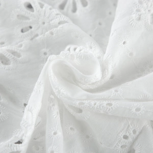 Dettaglio macro del tessuto in cotone bianco con ricamo floreale e pizzo sangallo