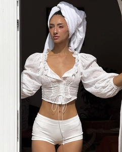 Dettaglio del top in cotone ricamato bianco con scollo a V a volant e lacci stile corsetto