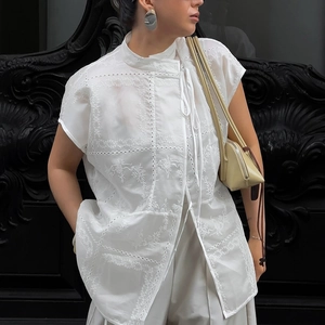 Detalle de blusa blanca con bordado calado y cuello mao con delicados lazos finos