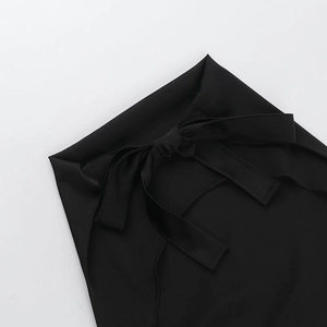 Détail d'un haut en satin noir avec une sangle de taille décorative en forme de nœud
