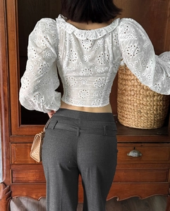 Dettaglio del ricamo floreale su un crop top in cotone bianco con orlo a balze