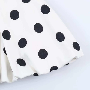 Detailansicht des schwarzen Polka-Dot-Musters auf weißem Stoff mit weicher Textur