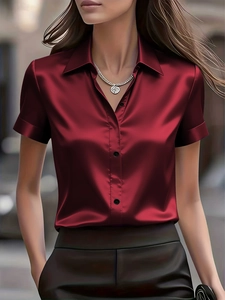Detail of red short-sleeved satin shirt showing silk texture and button-down collar