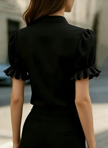 Detail view of black puff sleeves with ruffle accents and stand collar on short sleeve shirt