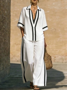 Women's white two-piece set featuring short sleeve shirt and wide leg pants with black trim