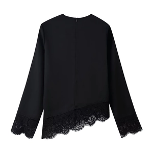 Detailed view of black long sleeve top featuring delicate lace trim and asymmetric hem design