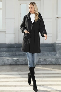 Outdoor street view of a long black hooded windbreaker featuring a drawstring waist detail