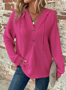 Detailed macro view of the fuchsia waffle knit texture and V-neck buttons on the hoodie