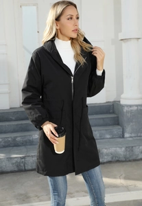 Outdoor street style of a long black hooded windbreaker with adjustable drawstring waist