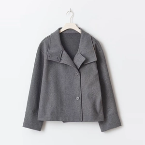 Detail of dark grey wool jacket featuring asymmetrical lapel and button closure