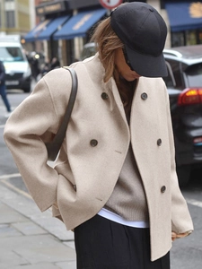 Detail van een beige wollen jas met dubbele knopen en een hoogwaardige dikke textuur in streetstyle