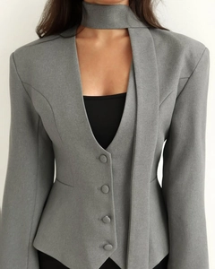 Détail d'un blazer gris cintré avec col en écharpe en V et boutons recouverts de tissu