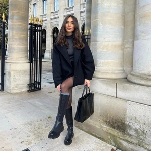 Minimalist black matte leather platform knee-high boots styled with a long coat