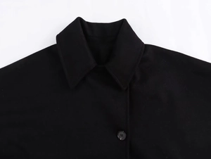 Close-up of lapel and resin button on a loose black wool jacket for women