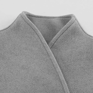 Detailopname van de kraag van een grijze wollen jas met focus op textuur en naden