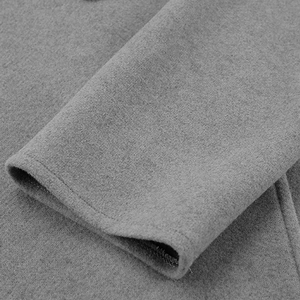 Detailopname van de mouw van een grijze wollen jas met dikke textuur details
