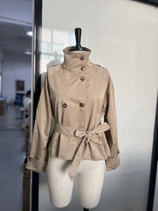 Détail d'un trench-coat court kaki à double boutonnage avec col montant et ceinture nouée