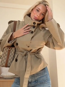 Detailed shot of khaki double-breasted short trench coat with stand collar and waist belt