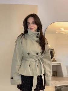 Detailed close-up of light khaki short trench coat with double-breasted buttons and belt
