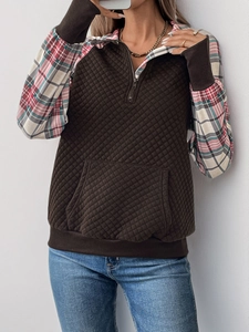 Detail of half-zip sweatshirt featuring quilted texture and red plaid patchwork sleeves