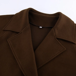 Primer plano del cuello de solapa y etiqueta de talla L en un abrigo de lana marrón