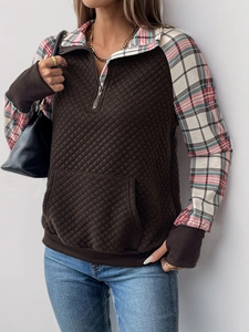 Detail of quilted brown pullover with plaid patchwork on the collar and sleeves